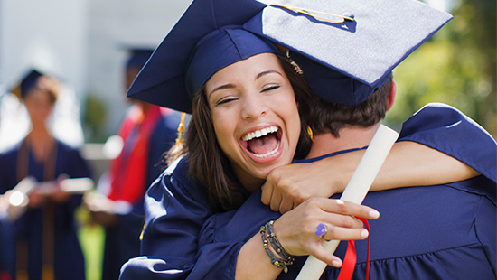 Woman and man embracing in graduation attire